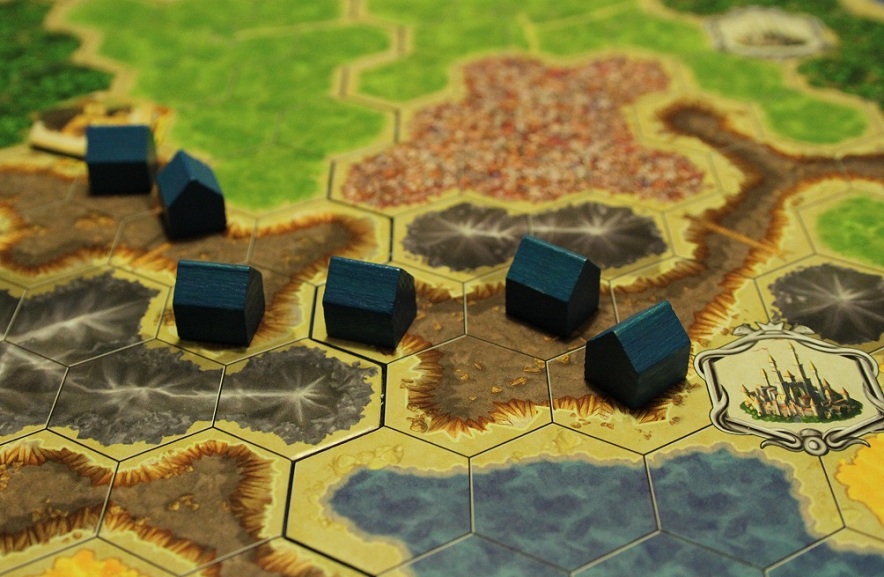 På billedet her, har den blå spiller i Kingdom Builder bygget sine huse, så de når hen til en storby (med sølvkant) i højre side og et specialfelt (med guldkant) i venstre side.